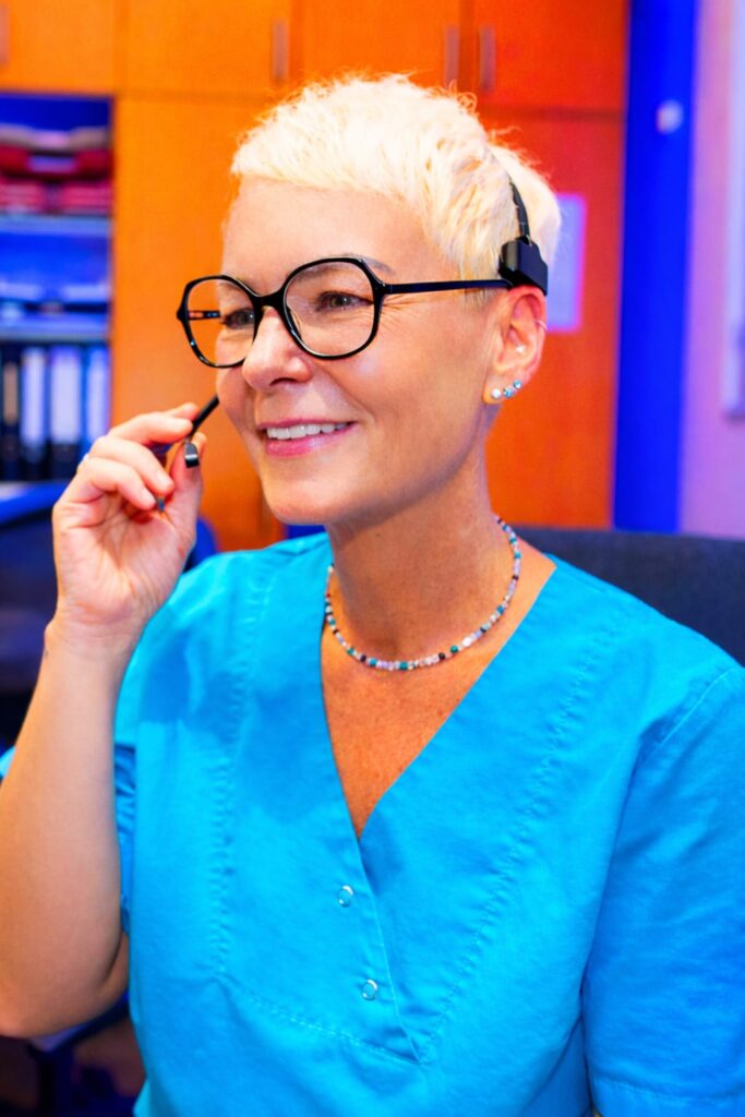 Freundliche Zahnärztin im blauen Kittel am Schreibtisch